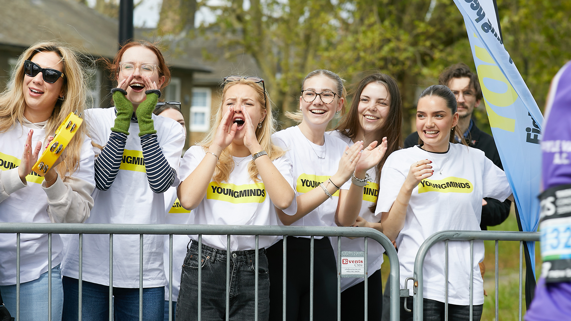 YoungMinds staff cheering marathon runners on from the side line in YoungMinds t-shirts and with YoungMinds banners.