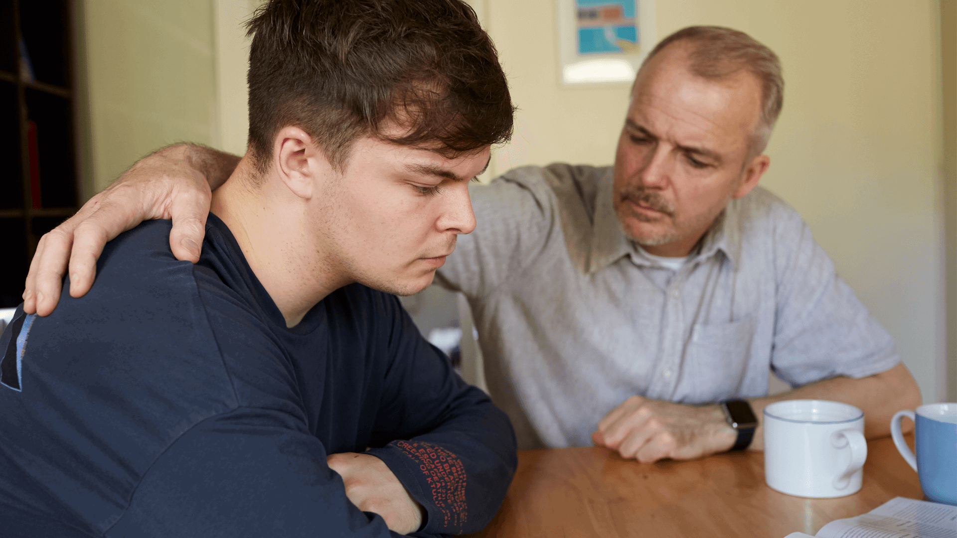 A father comforts his son at the table