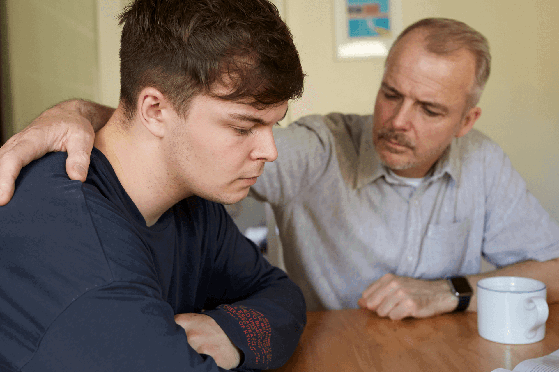 A father comforts his son at the table