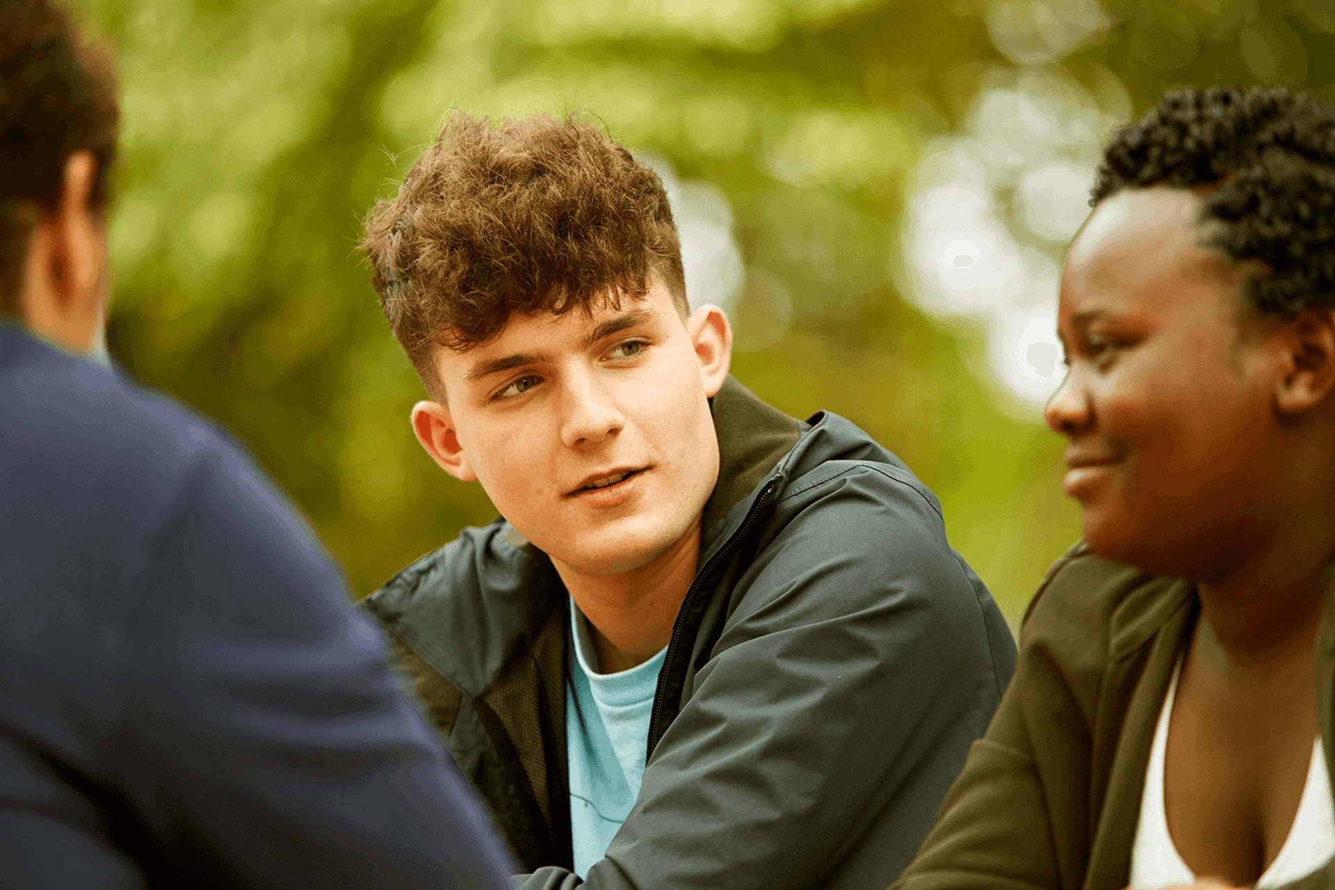 Three young people sitting together in a park.