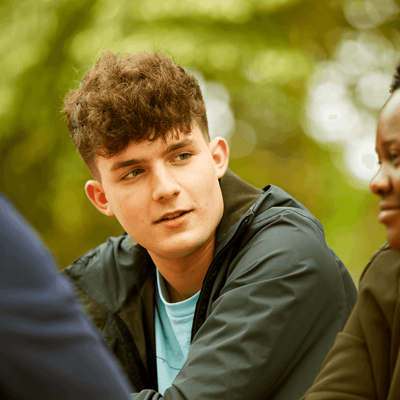 Three young people sitting together in a park.