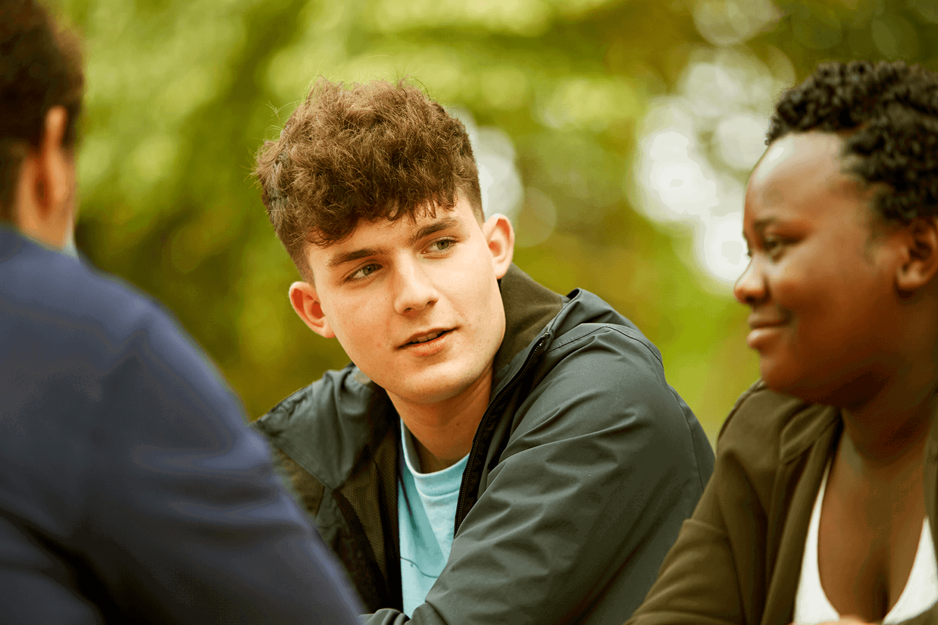 Three young people sitting together in a park.