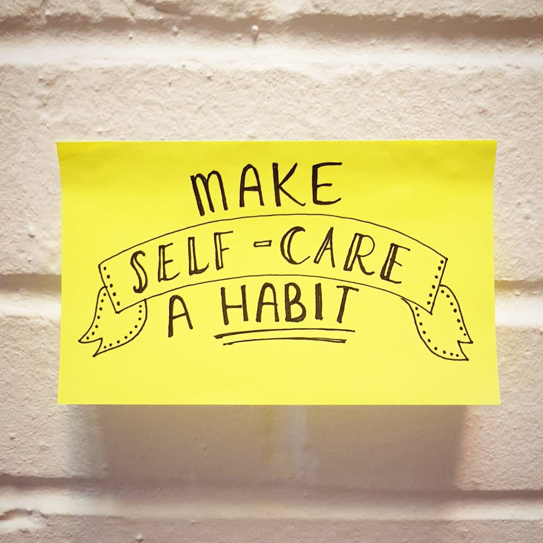 Instagram artwork by @youngmindsuk. A yellow post it note sits on a white wall with a hand written note of 'make self-care a habit'.