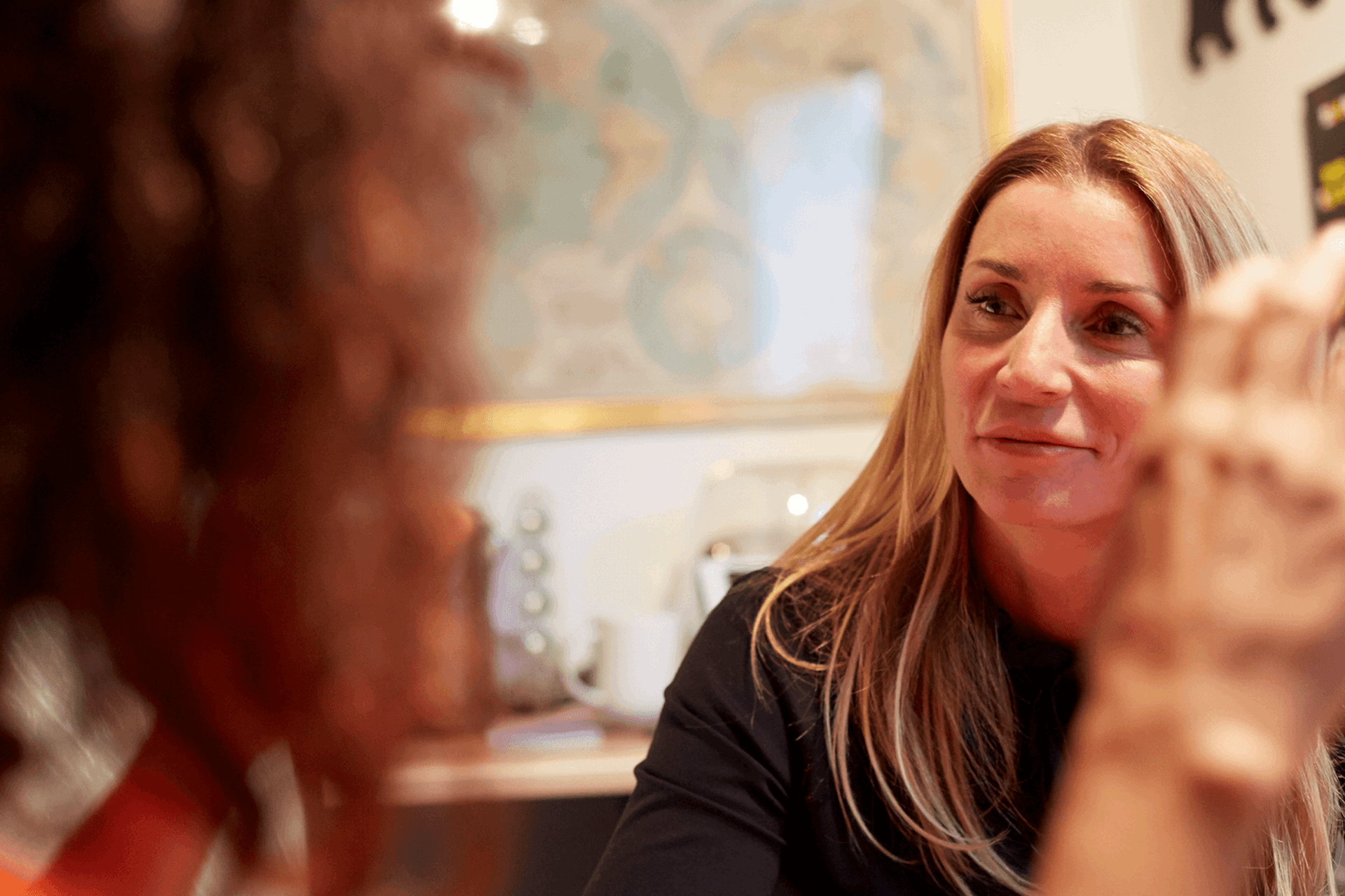 Two women sitting in a room chatting socially