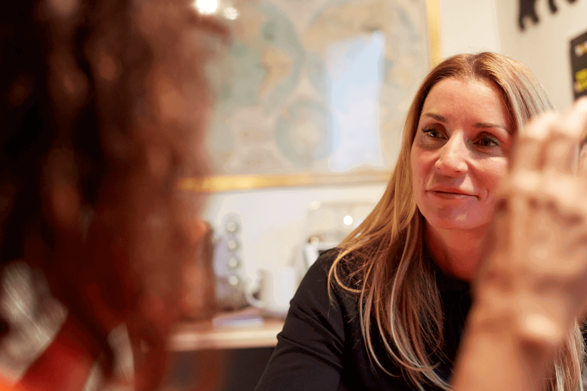Two women sitting in a room chatting socially 