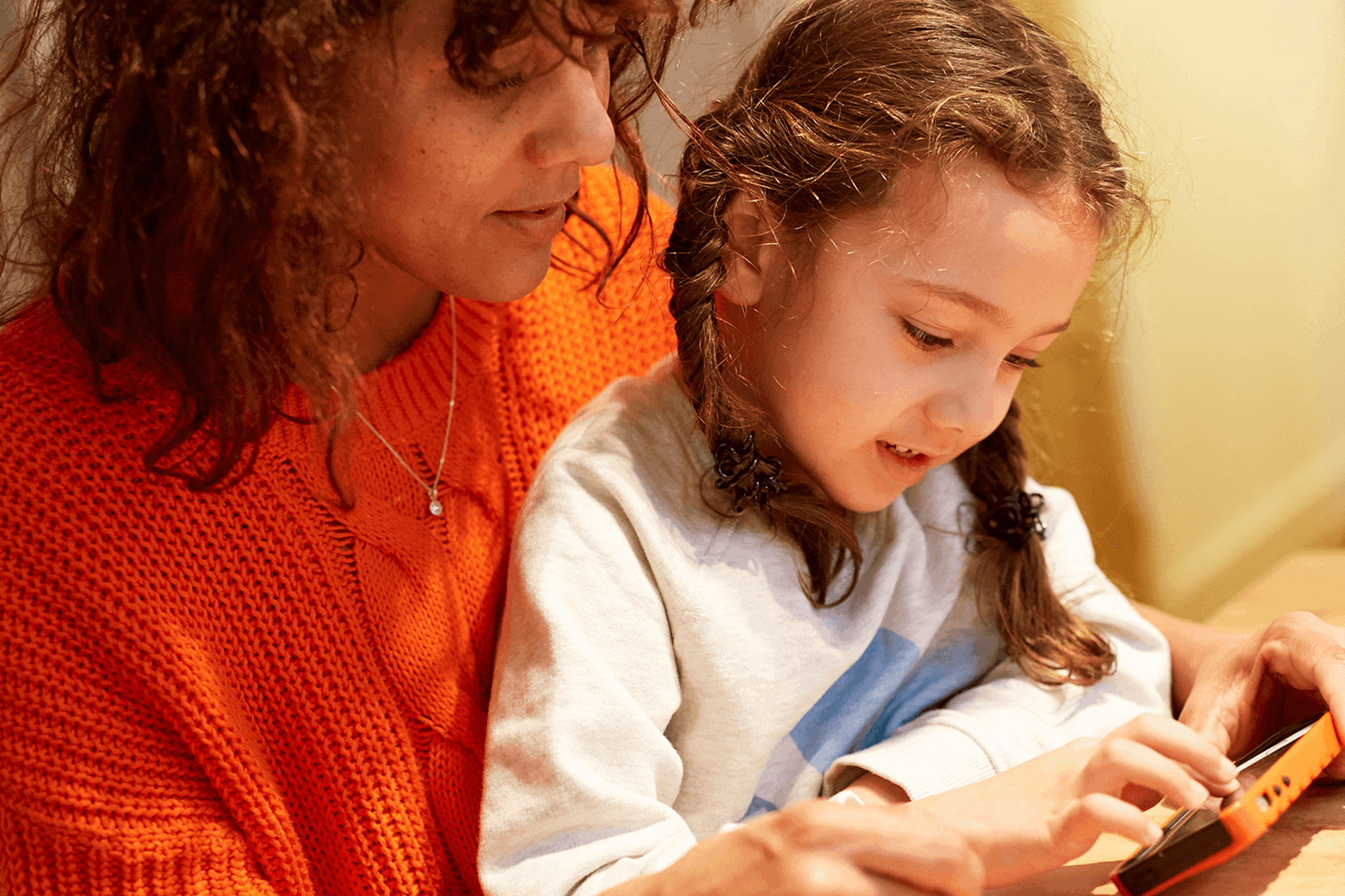 Parent and child looking at a mobile phone together.