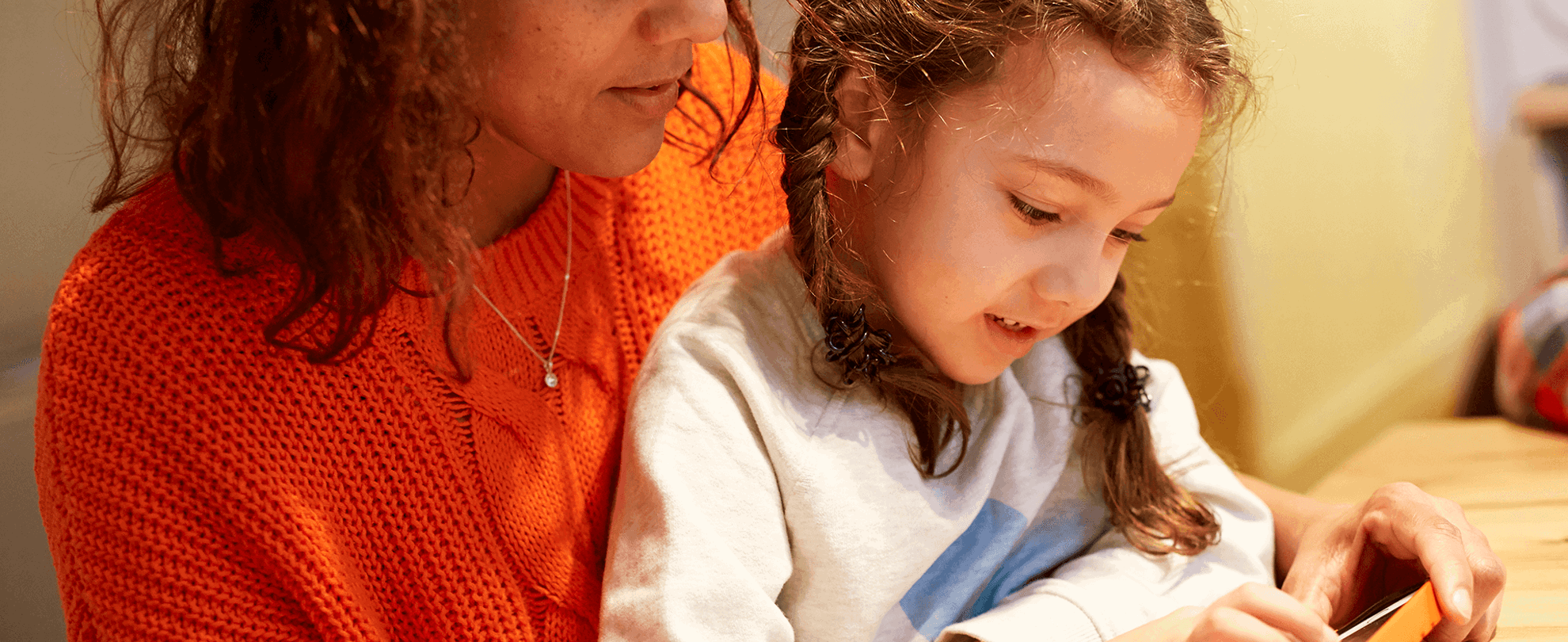Parent and child looking at a mobile phone together.