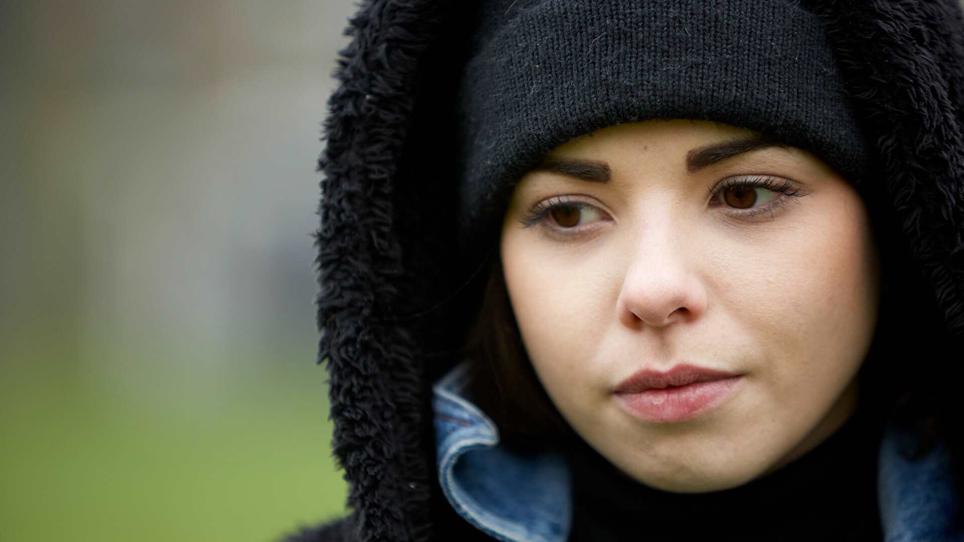 close-up-of-a-girl-wearing-black-beanie-looking-worried-with-eyes-looking-down