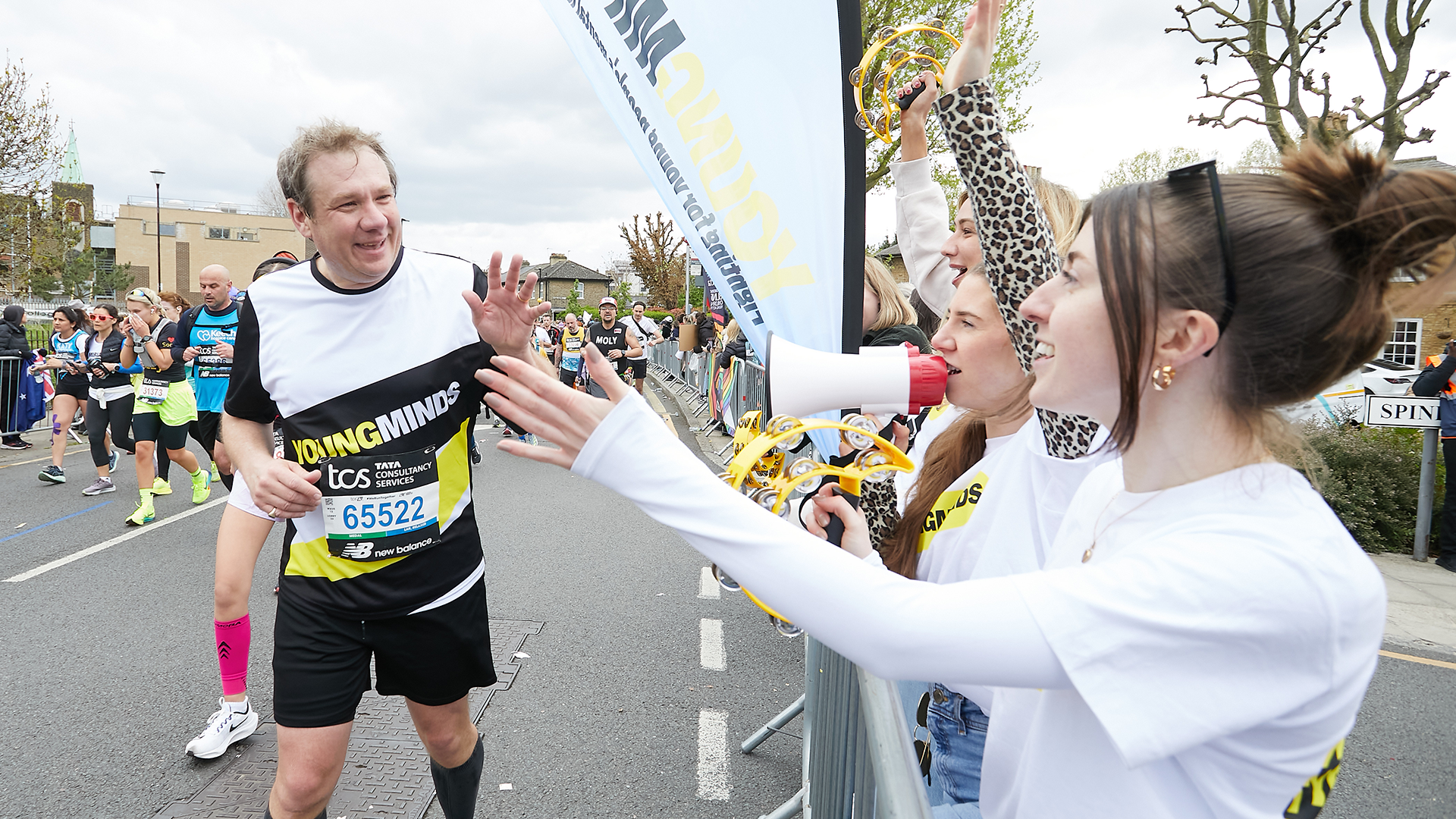 A YoungMinds marathon runner being supported by YoungMinds staff on the side line.