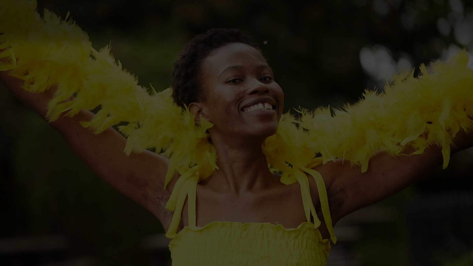 A person wearing a yellow vest and a yellow feather bower celebrating #HelloYellow