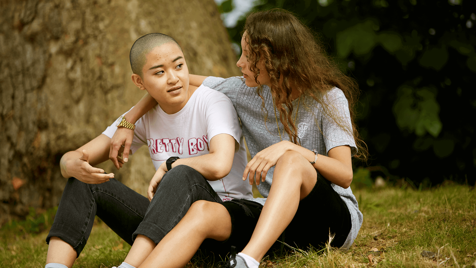 Two young people sitting in the grass together.