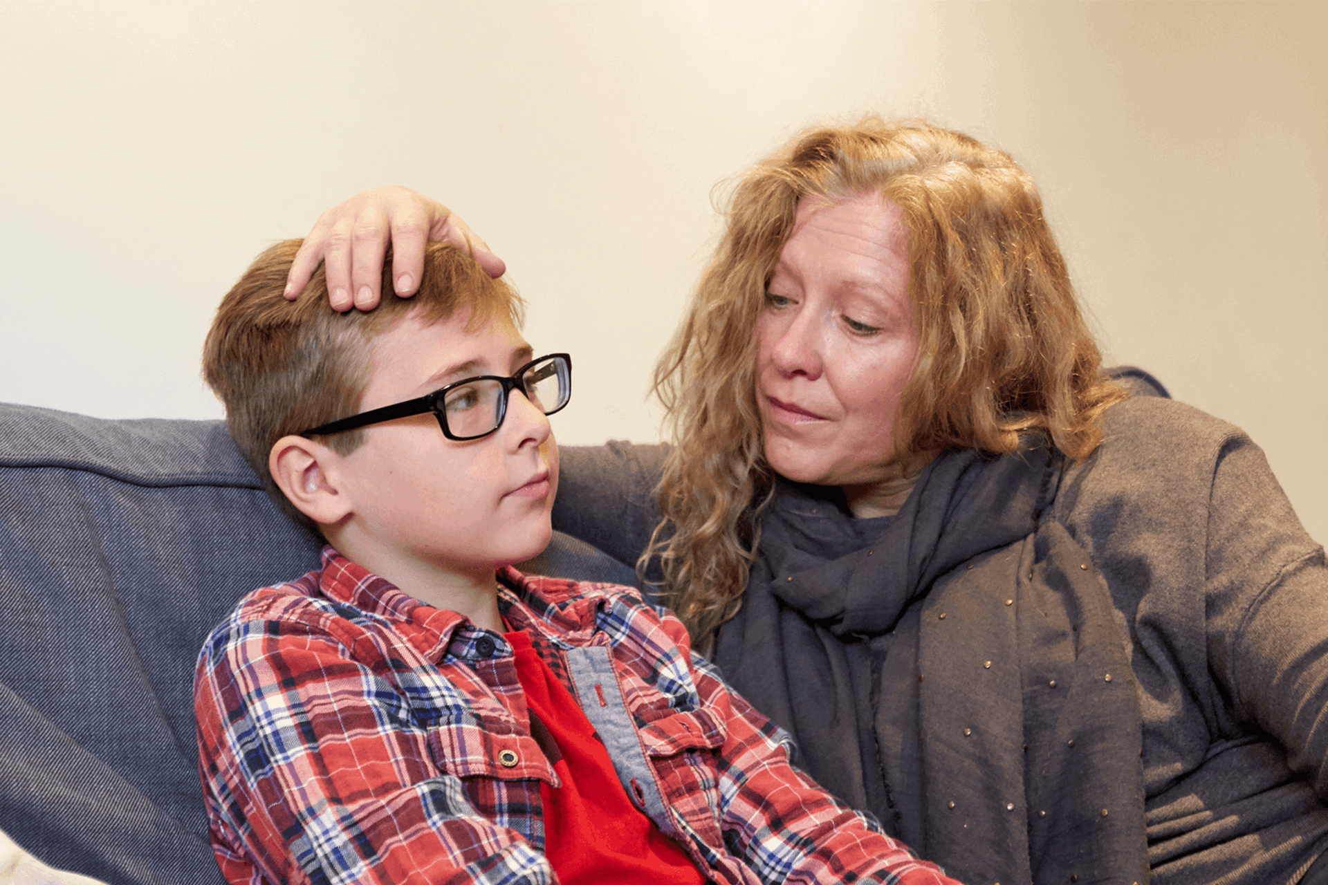A mother reassures her son by putting her hand on his head