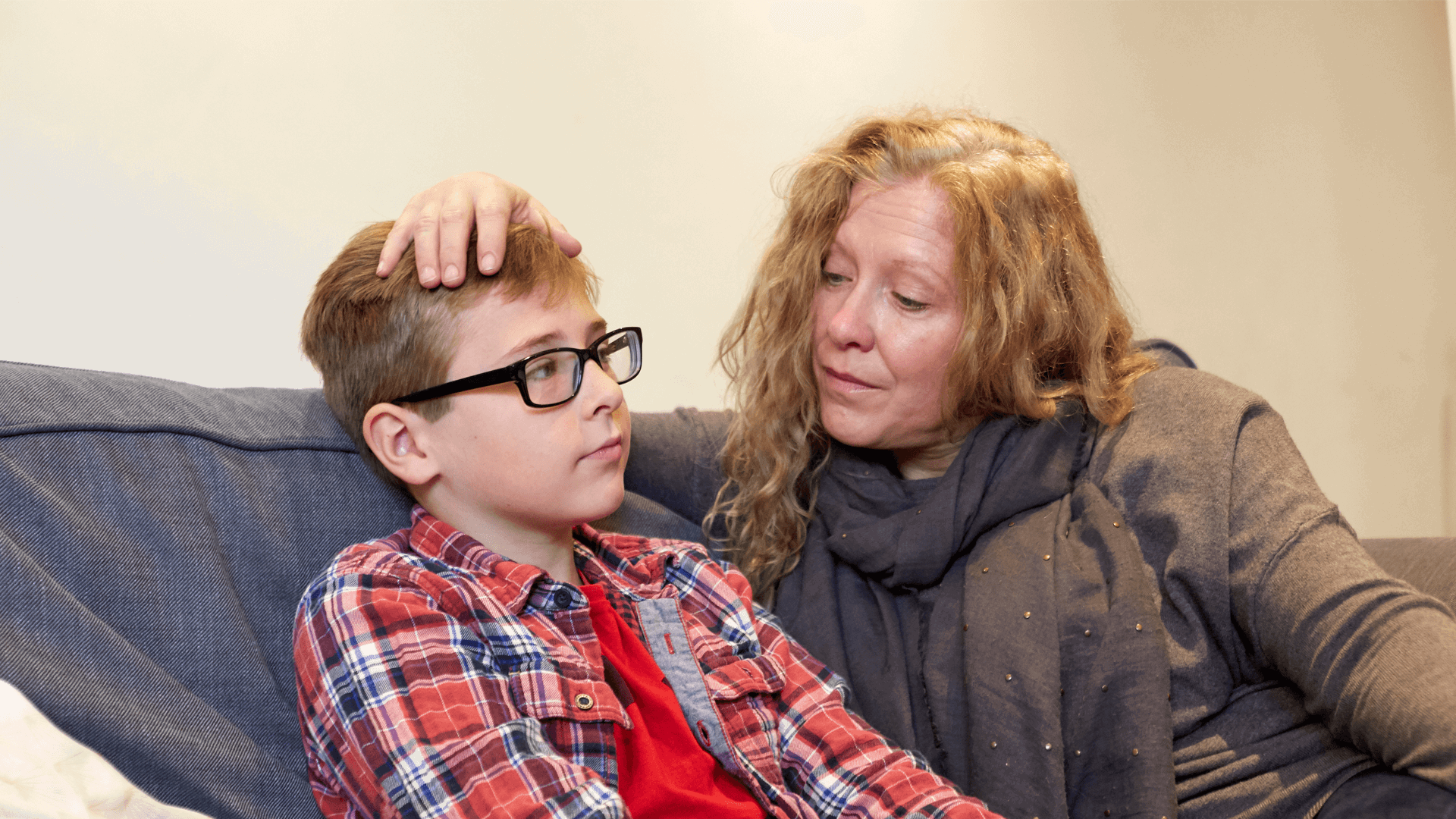 A mother reassures her son by putting her hand on his head