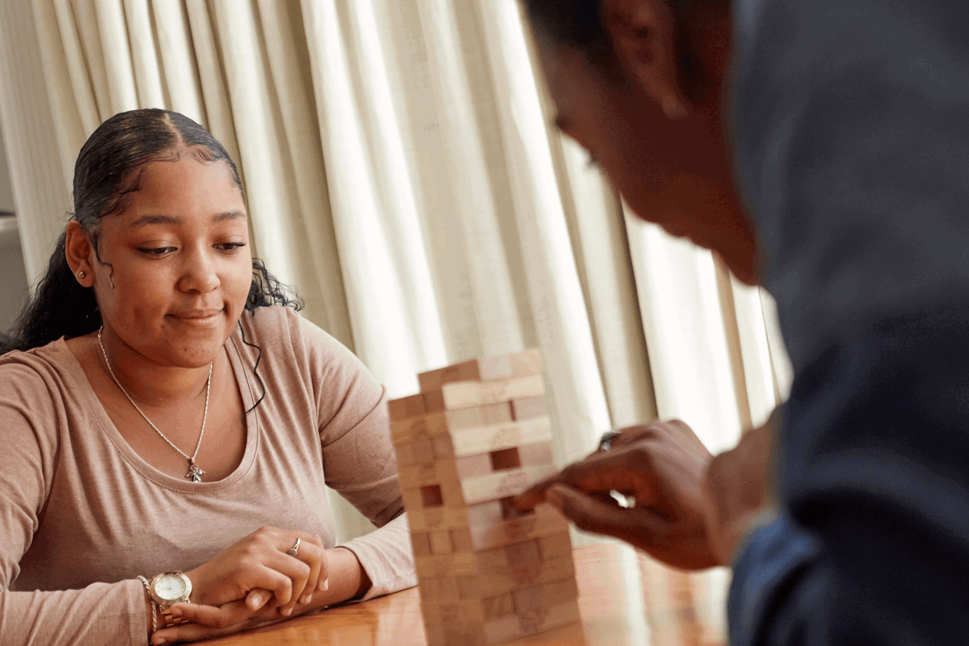 Two people playing jenga at a table