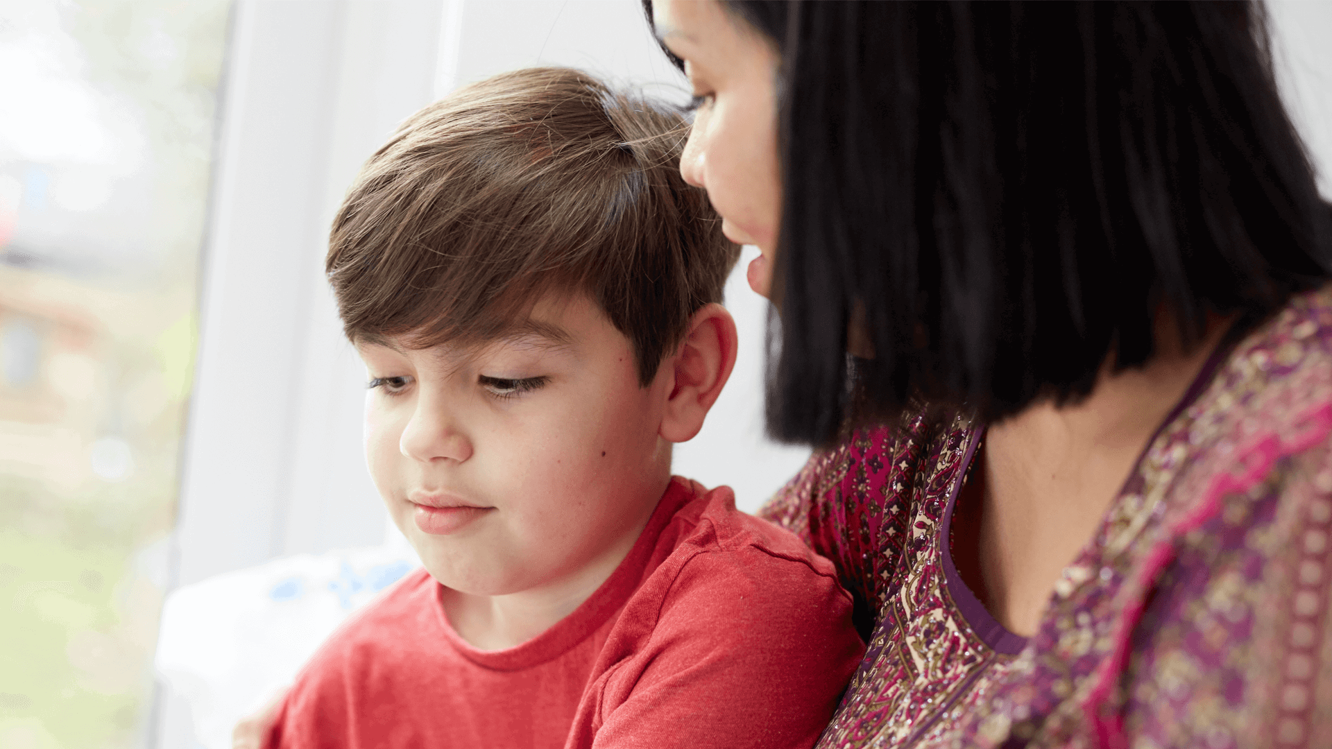A mother looking at her young son by a window