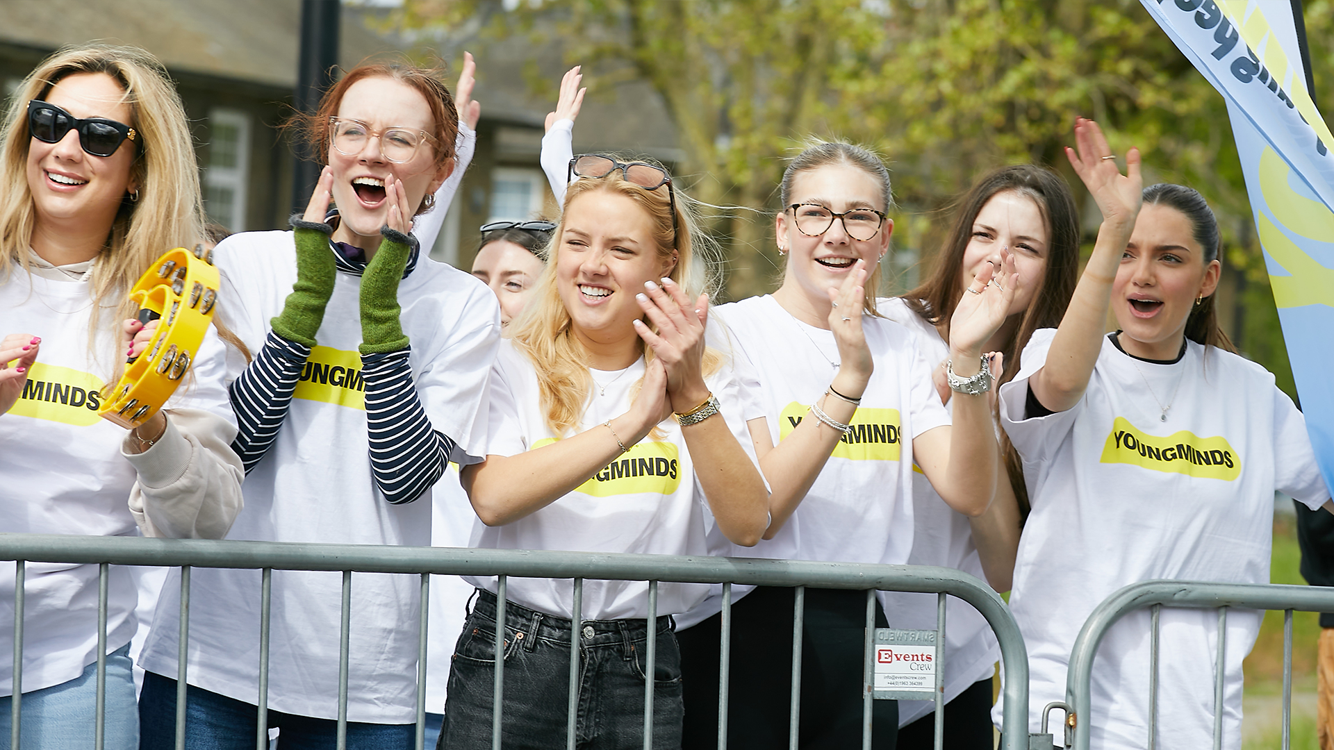 YoungMinds staff cheering marathon runners on from the side line in YoungMinds t-shirts and with YoungMinds banners.