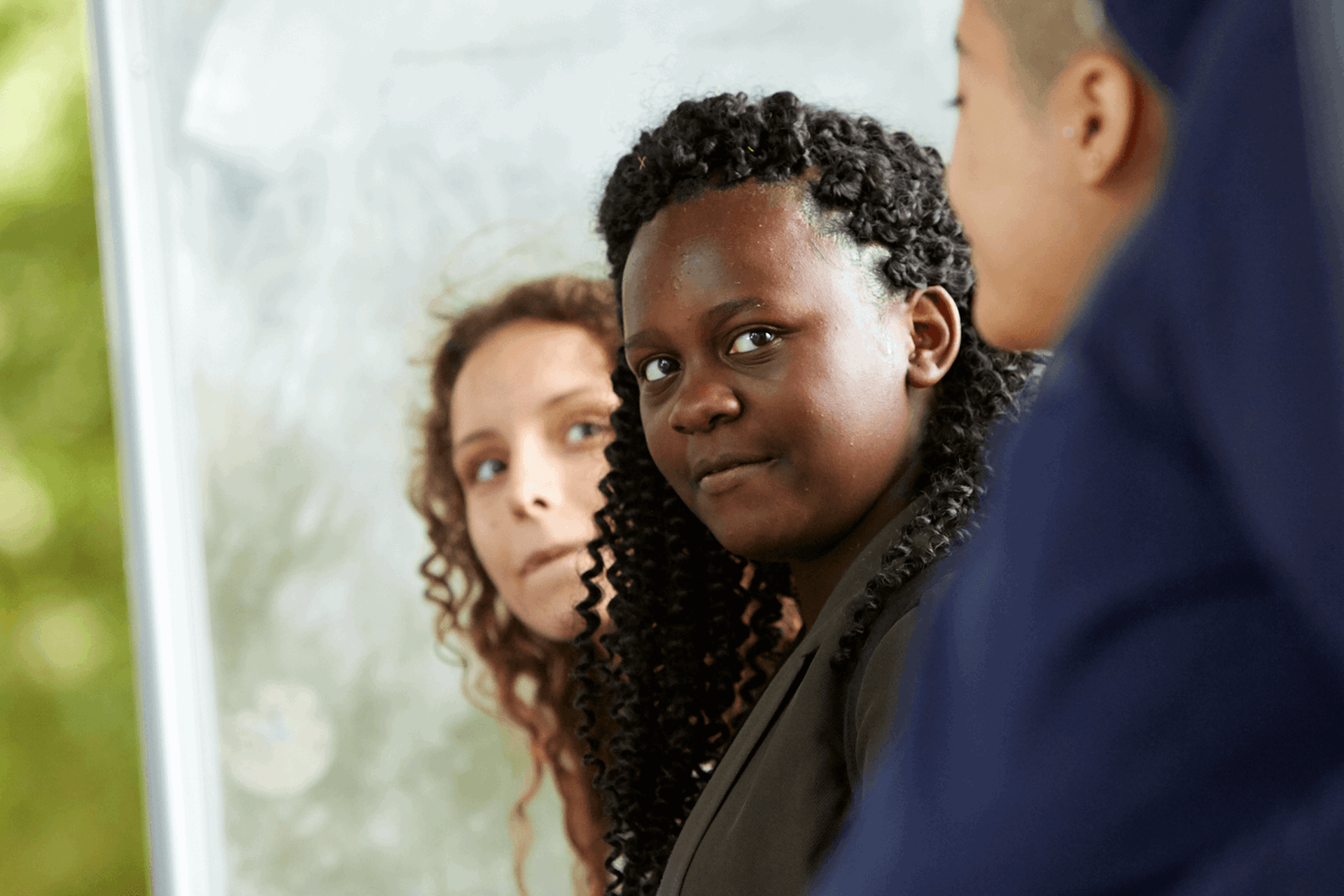 Three young people sitting in a row and talking together in a park.
