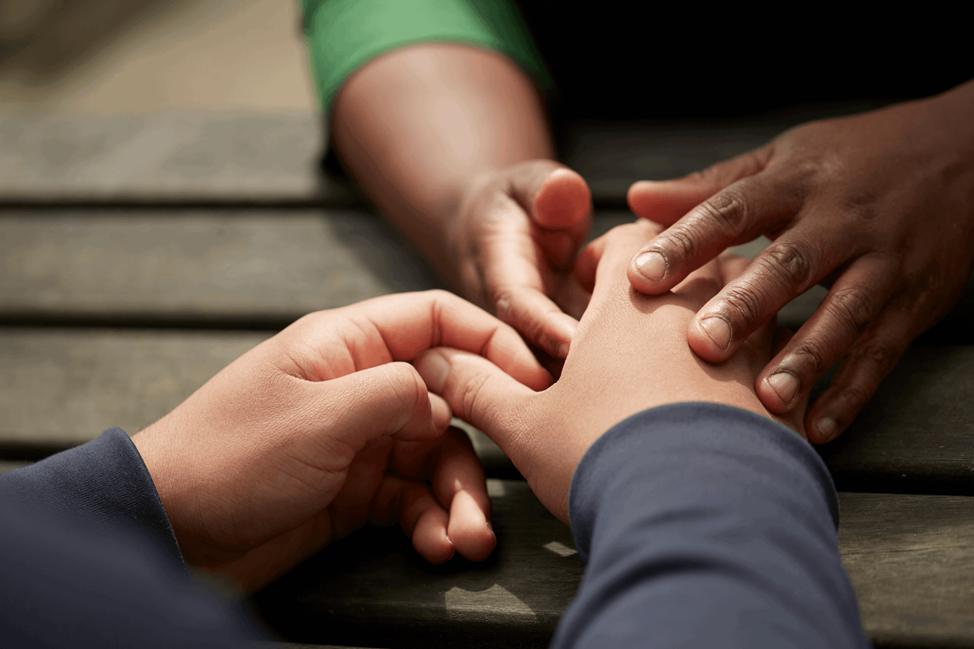 Two people holding hands over a table outside