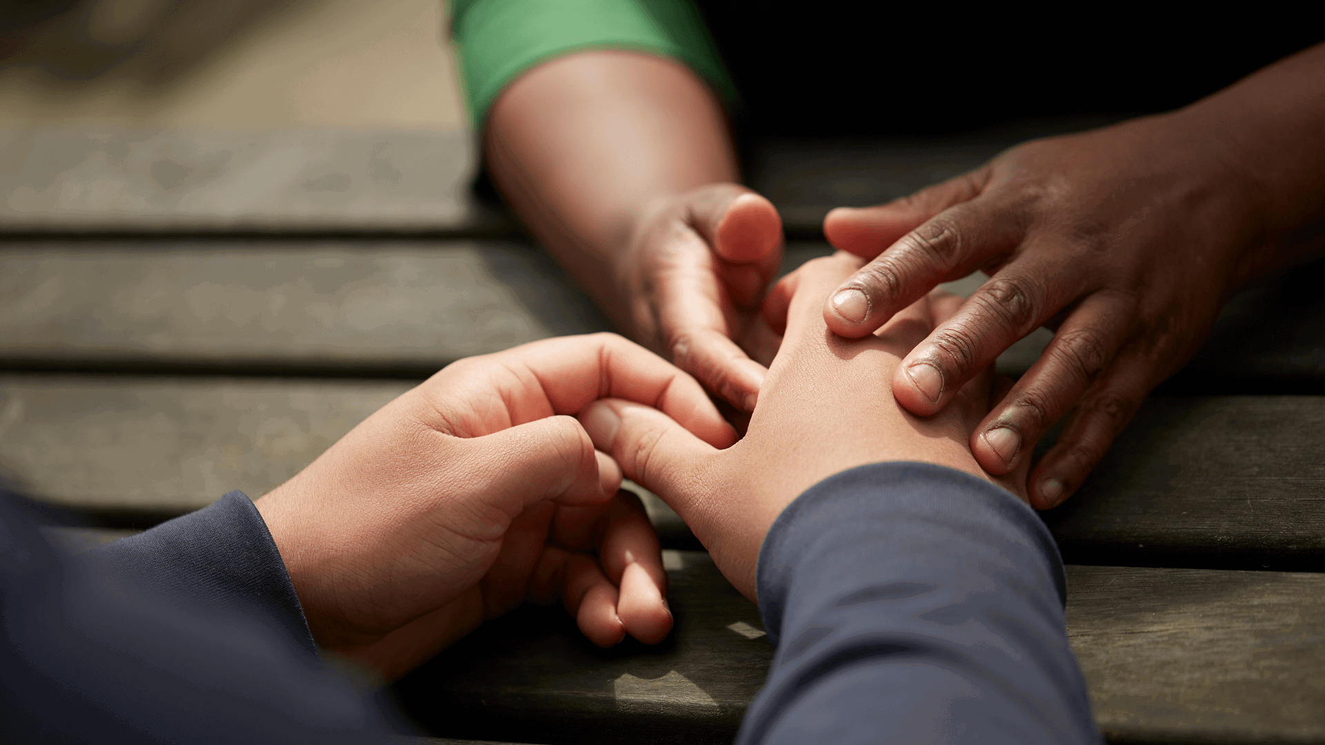 Two people holding hands over a table outside 