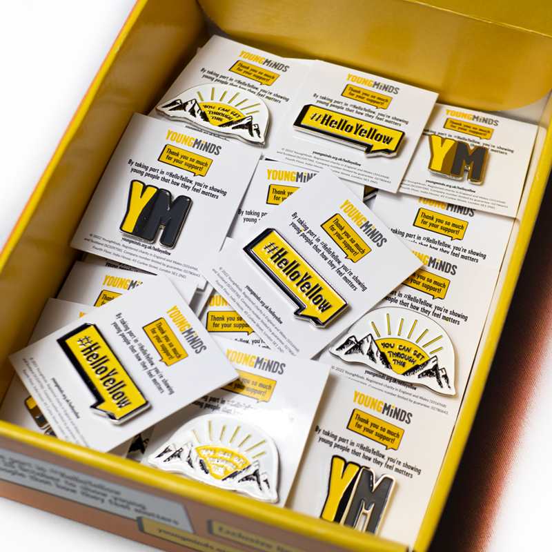 A close up of inside the box showing a number of ​#HelloYellow pin badges,​ ​YoungMinds pin badges and​ ​'You can get through this' pin badges.