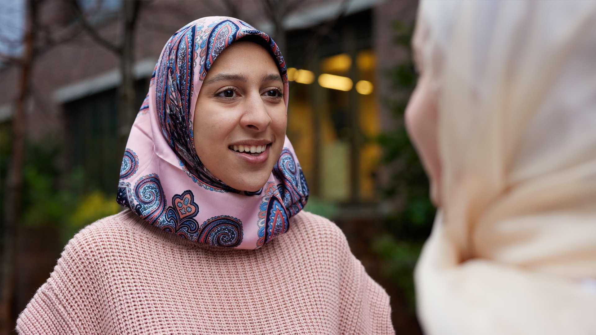 Two young Muslim women in headscarves talking.