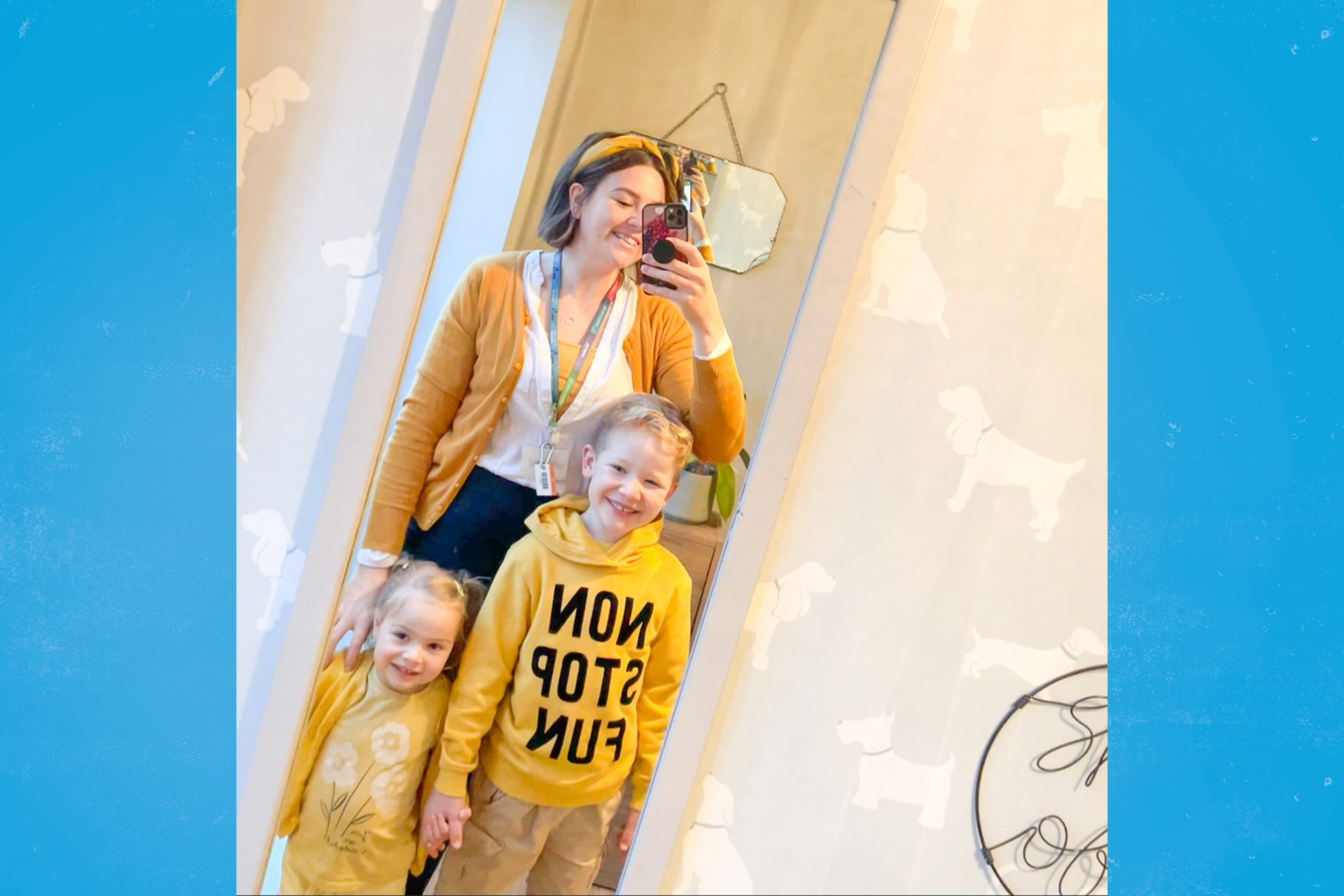 A staff member and two children all wearing yellow and posing for a photo in the mirror.