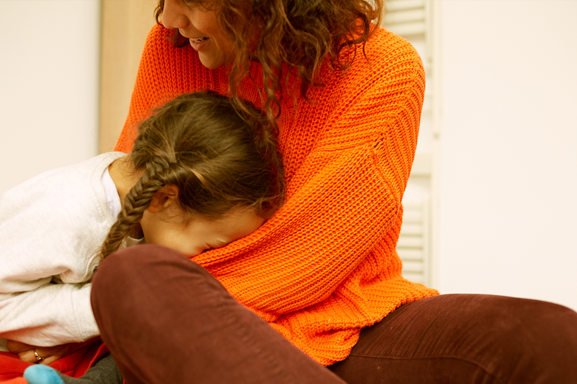 A child laughing with her head in her mum's lap.