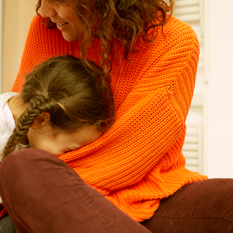 A child laughing with her head in her mum's lap.