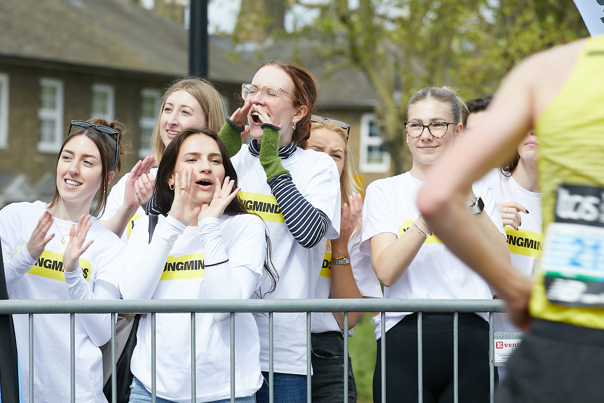 YoungMinds staff cheering marathon runners on from the side line in YoungMinds t-shirts and with YoungMinds banners.