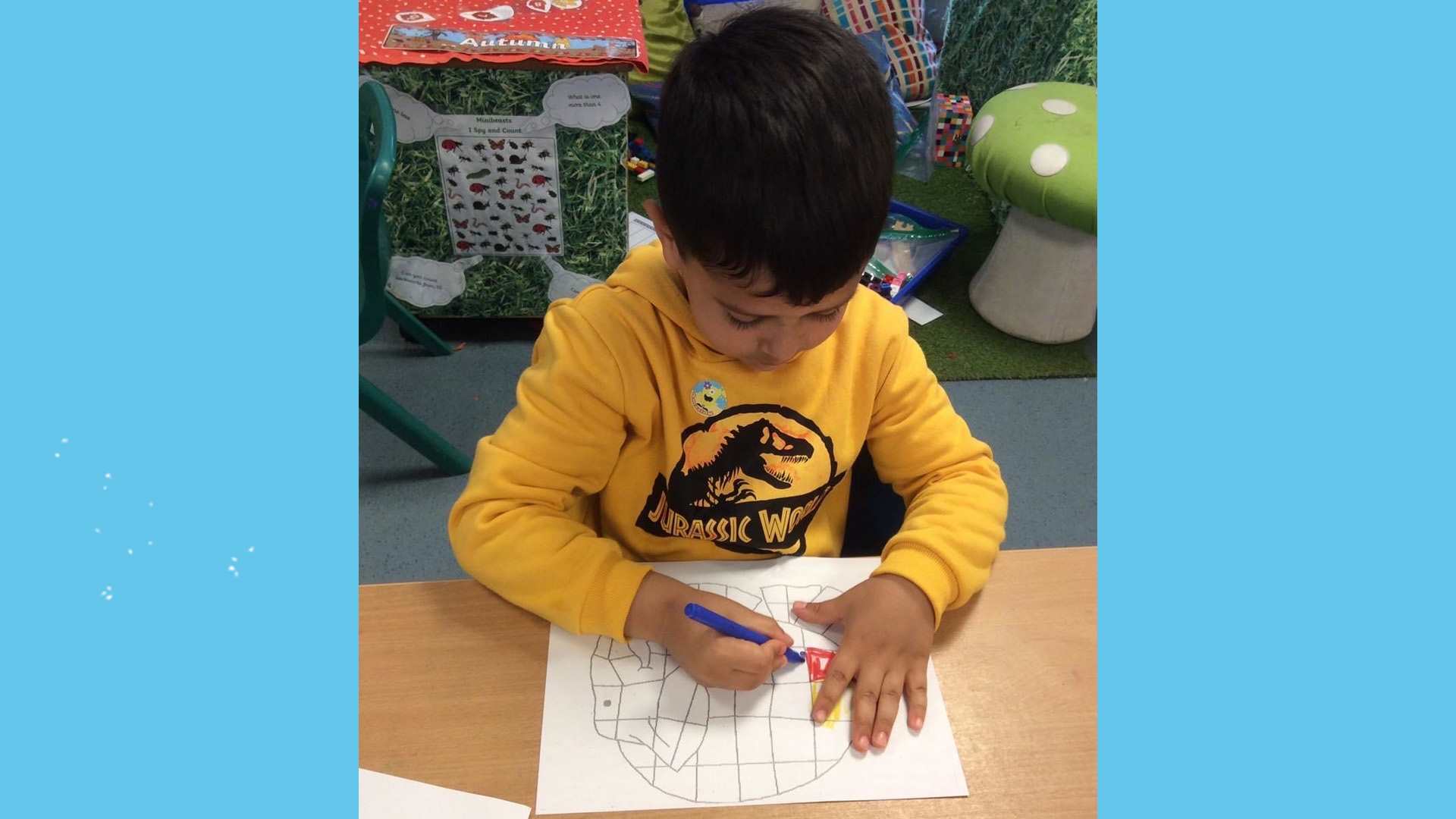 A child in a yellow jumper colouring in.