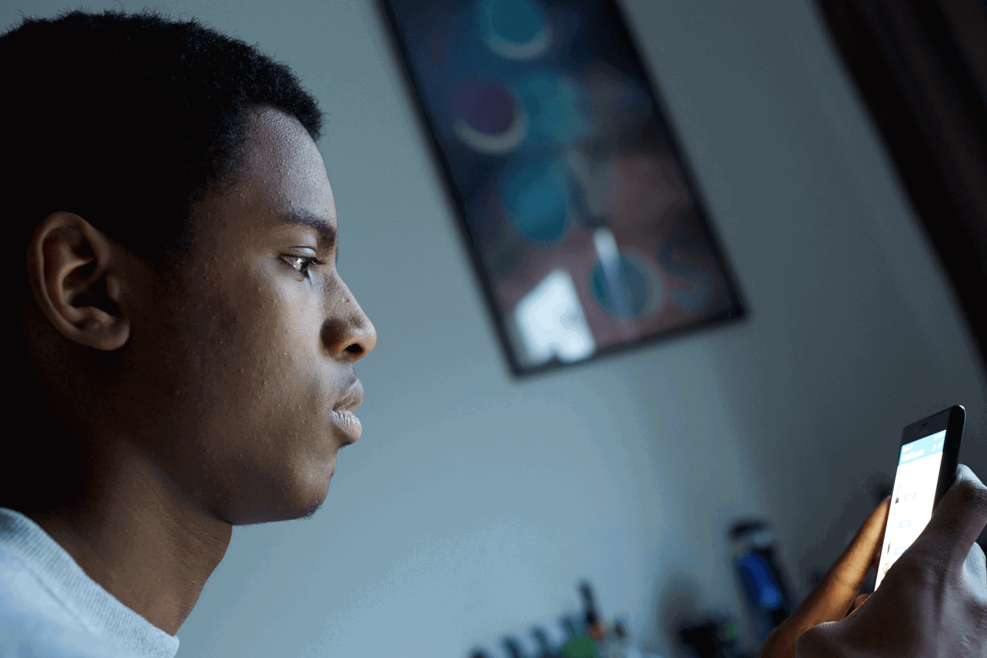 A young person in their bedroom looking at their phone.